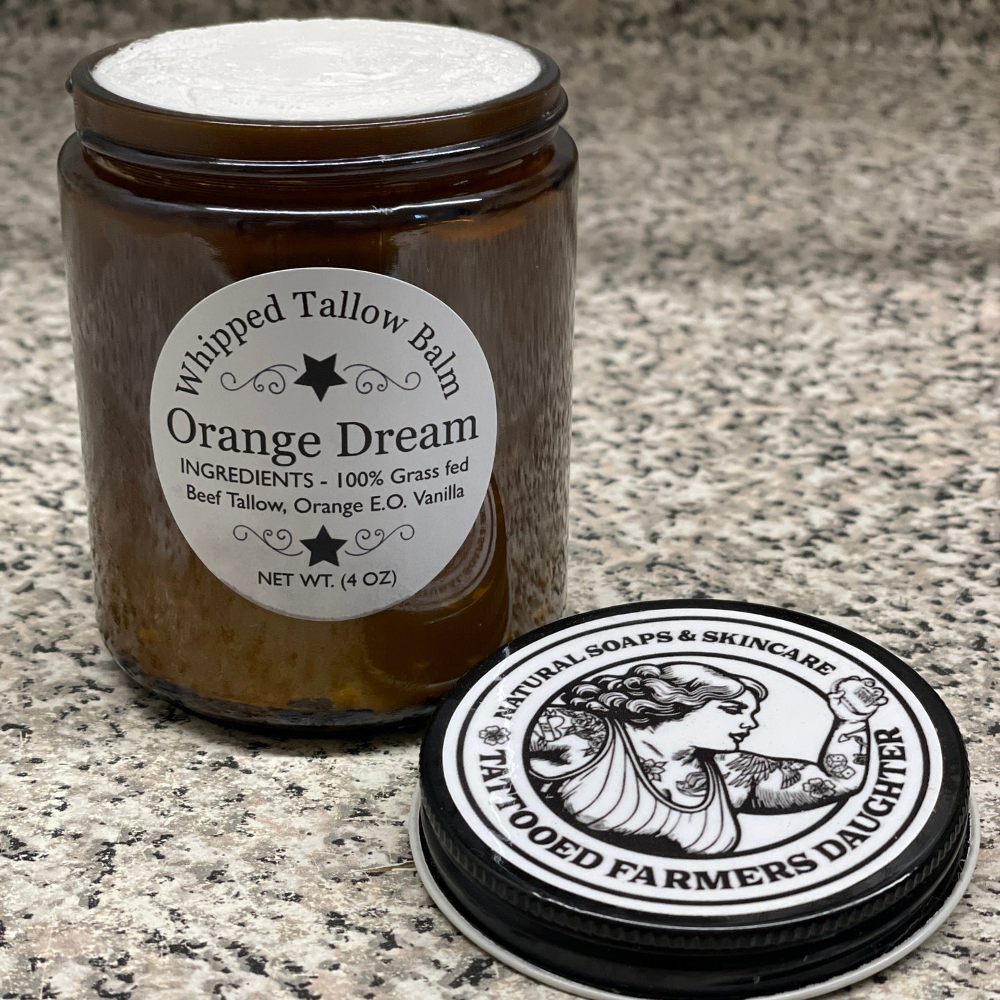 Tattoo balm container with 'Orange Dream' label on a textured surface